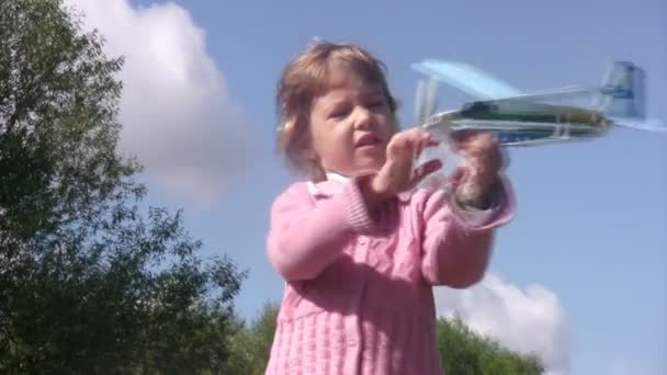 Menina brinca com avião de brinquedo e lançá-lo no parque. Dia de verão ensolarado . — Vídeo de Stock