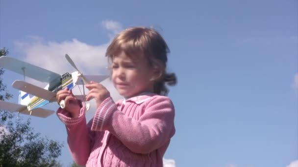 Κοριτσάκι παίζει με παιχνίδι αεροπλάνο, αεροπλάνο έλικα στροφές. ηλιόλουστη καλοκαιρινή μέρα. — Αρχείο Βίντεο