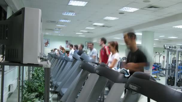 Les gens regardent la télévision sur les tapis roulants au club de fitness Multisport — Video