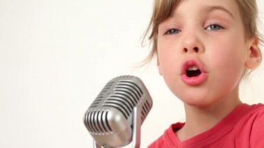 güzel kız beyaz zemin üzerinde mikrofon şarkı söylüyor