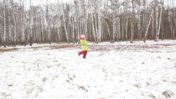 緑ジャケットを着た小さな女の子が冬の木になっています。. — ストック動画