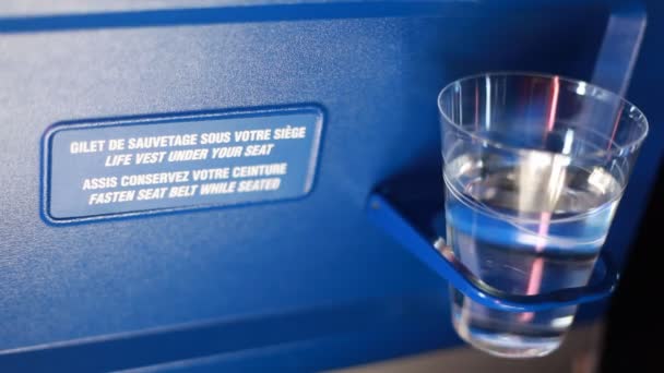 Vidro de água de pé no suporte para avião cadeira traseira — Vídeo de Stock
