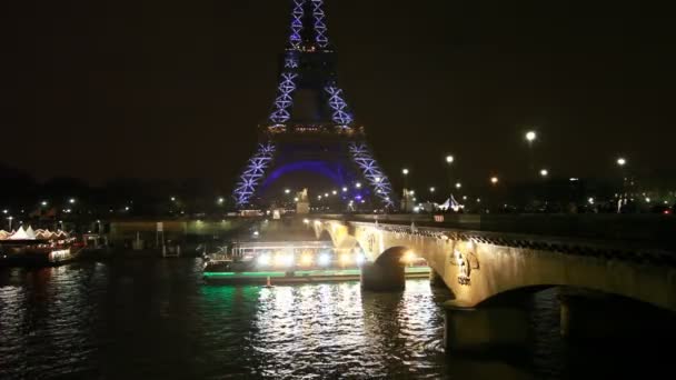 Eiffel Tower, under Pont d'Iéna bridge on Seine glowing ship floats — Stock videók