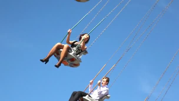 Couple are on merry-go-round on blue sky background. — Stock Video