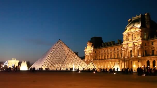 Tourists walk on square in front of Louvre in night — Stock Video