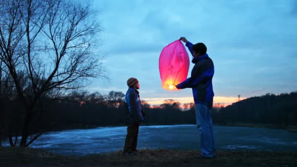 Mannen innehar kinesiska lantern vintern skog, dess son ser ut och berör den — Stockvideo