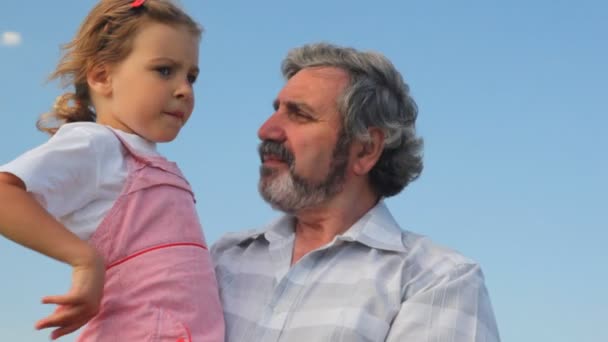 Oudere man met zijn kleindochter op handen — Stockvideo