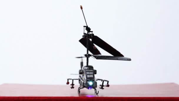 El helicóptero de juguete está en la mesa, sus cuchillas comienzan a girar, luego vuela hacia arriba — Vídeos de Stock