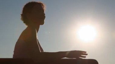 öğleden sonra gökyüzüne karşı bankta oturan kadın