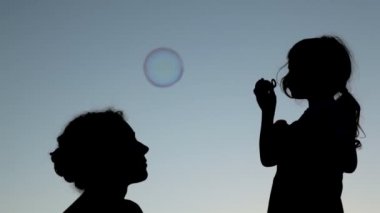 küçük kız kadar sabun köpüğü üfleme yakınında oturan Anne