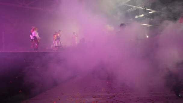 Dancers appear on illuminated stage in smoke — Stock Video