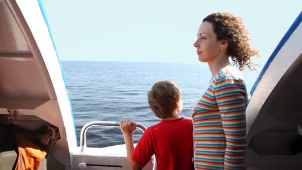 Мать и сын стоят рядом с быстро движущимся судном на подводной крыле в море — стоковое видео