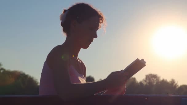 Woman sitting on bench and reading book — Stock Video