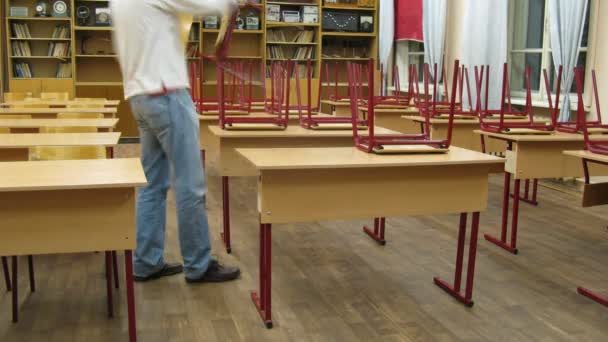 Man places books on school desks and then collects them — Stock Video