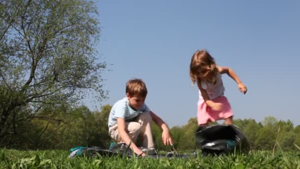 Pojken och flickan börjar att veckla upp tält — Stockvideo