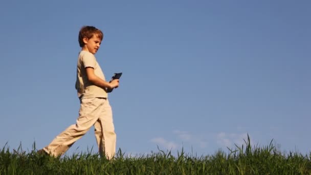 Junge kommt auf Gras, klickt auf Klappbrett — Stockvideo