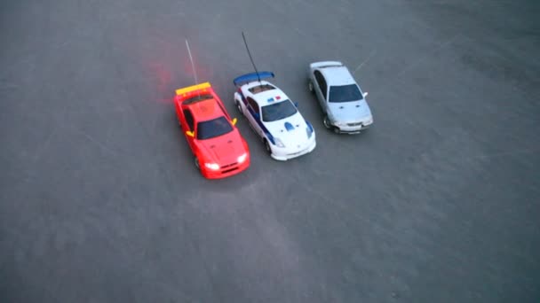 Radio-controlled toy cars start and go out of frame on pavement — Stock Video