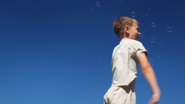 Jongen golven zijn armen, kloppen veel vliegen naar hem bubbels — Stockvideo