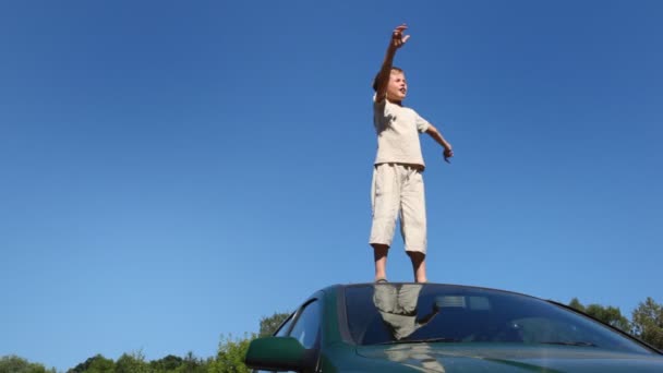 Boy stands on roof of passenger car with his hands wide apart — Stock Video