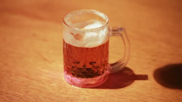 Transparent cup of beer standing on wooden table — Stock Video