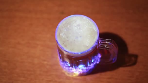 Copo transparente de cerveja em pé sobre mesa de madeira — Vídeo de Stock