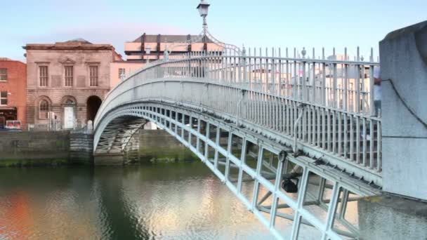 People crosses The Ha'penny Bridge through the Liffey river — Stock Video