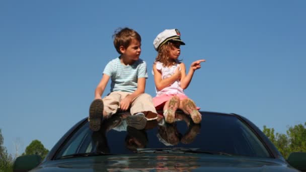 Boy and girl sit on roof of car — Stock Video