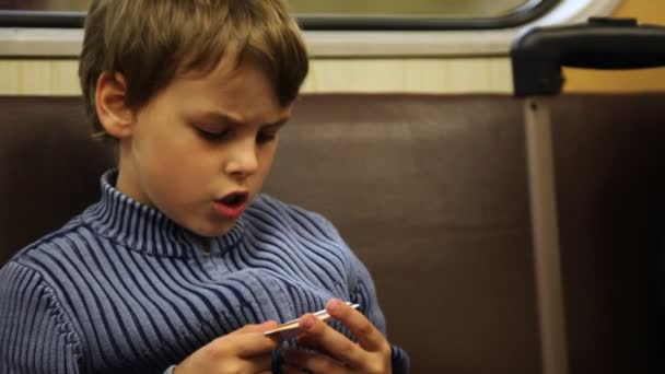 Boy sits and studies yawning ticket in moving subway train — Stock Video