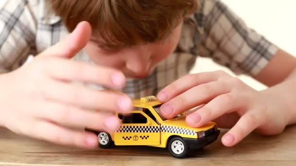 El chico jugando con el coche de juguete taxi — Vídeos de Stock