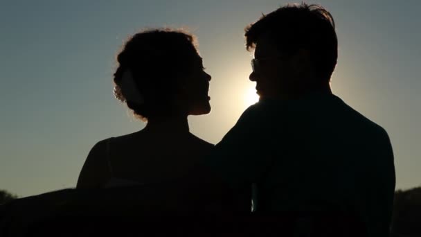 Visão traseira de abraçar casal senta-se no banco e fala — Vídeo de Stock