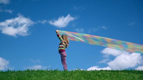 Menina fica com tecido de arco-íris nas mãos — Vídeo de Stock