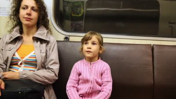 Mother with little daughter sit in riding subway train — Stock Video