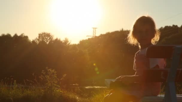 Ragazza seduta sulla panchina e voltando le pagine del libro — Video Stock