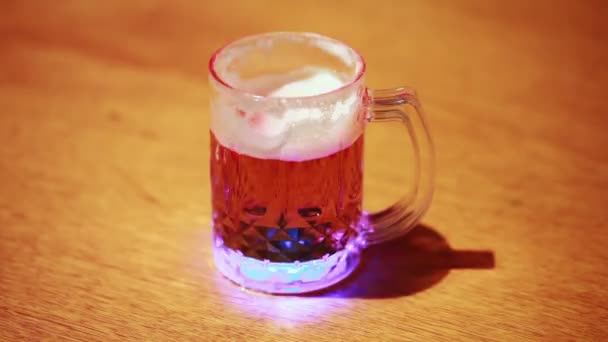 Transparent cup of beer standing on wooden table — Stock Video