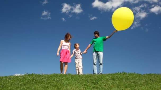 Famiglia che tiene le mani di bolla gialle giù collina — Video Stock