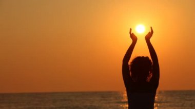 Sahilde duran, güneş onun elinde tutan kadın