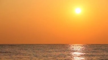 sessiz deniz dalgaları üzerinde turuncu gökyüzü günbatımı