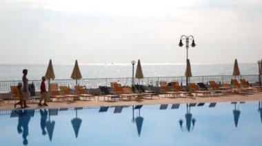 Sabaha karşı deniz havuzu boyunca aile yürür