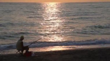 adam balıklar ve günbatımı sahil üzerinde otururken gözlemler