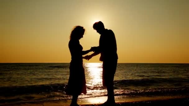 Мальчик и девочка стоят на пляже, силуэты на закате, часть 2 — стоковое видео