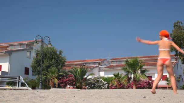 Frau mit Lächeln dreht Kreis entlang der Hütten am Strand — Stockvideo