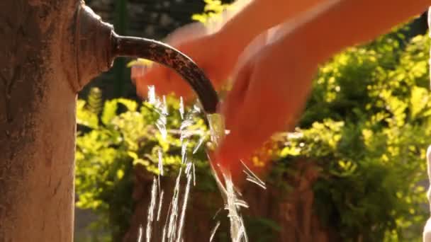 Woman washes her hands in stream of water from old rusty tap — Stock Video