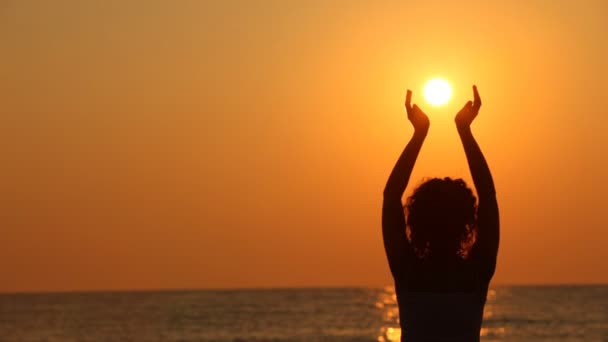 Mulher em pé na praia, segurando o sol em suas mãos — Vídeo de Stock