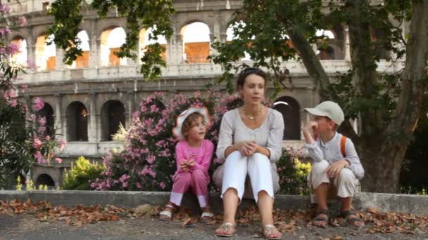 Žena vypráví příběh dívky a chlapce sedět ve stínu stromu před Koloseum — Stock video