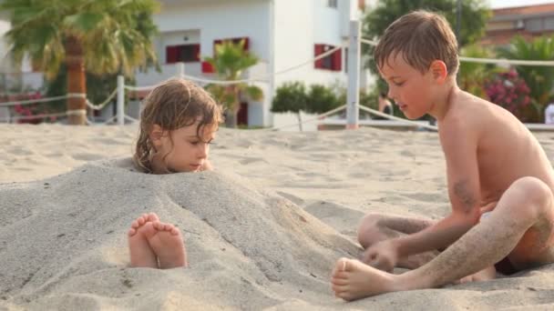 Играя старший брат падает сестра с песком — стоковое видео