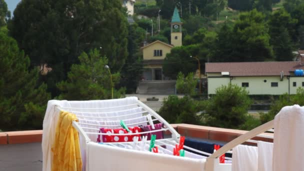 Menina pendura roupas lavadas para secar na varanda — Vídeo de Stock