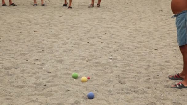 Cinco hombres en chanclas lanzan bolas por turnos en la playa — Vídeo de stock