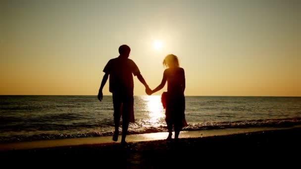 Jongen en meisje gaan op strand hand in hand voor zee, silhouetten op zonsondergang, part1 — Stockvideo