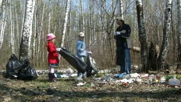 Los niños y su padre recogen basura en bolsas de basura en el bosque — Vídeos de Stock