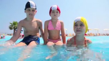 oğlan ve kız havuzda otururken, çocuk su sıçramalarına